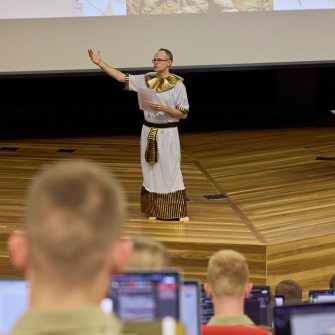 Lecturer dressed as Pharaoh gesturing dramatically